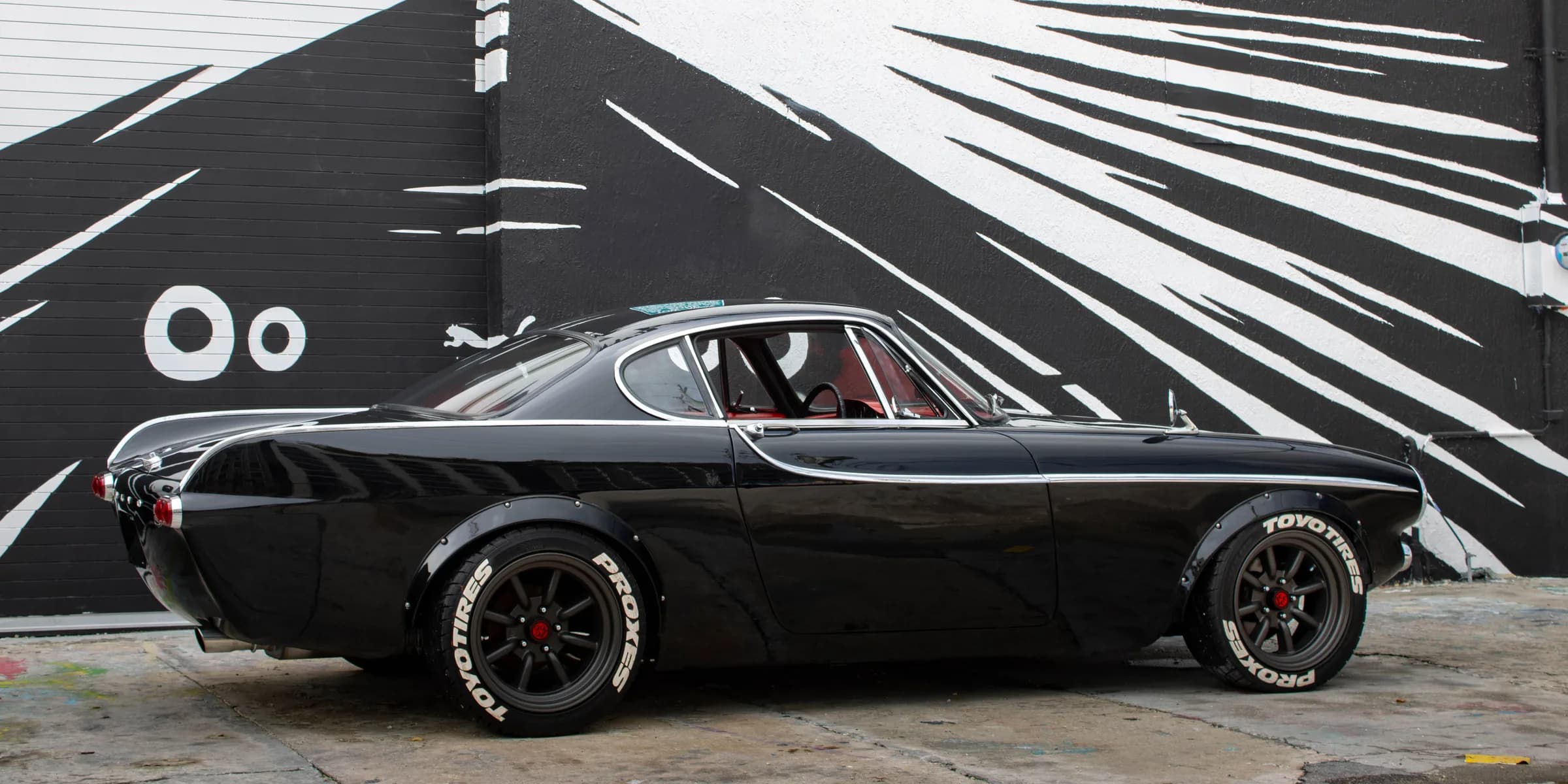 The Sinner, Ken Russell's 1965 Volvo 1800S, photographed in profile against a painted mural wall